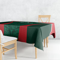 Green tablecloth with red side band, draped over dining table in angled view