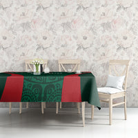 Green tablecloth with red corner bands and patterned center on table against wall