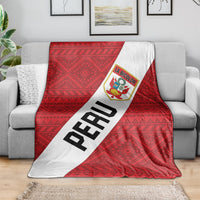 Red football blanket draped on gray sofa, white PERU stripe with La Bicolor crest