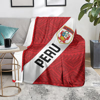 Red football blanket on gray couch, white PERU stripe and La Bicolor crest