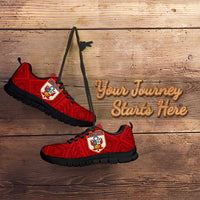 Red lace-up football sneakers with black sole and crest emblem on patterned upper.