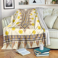 Cream blanket with yellow flowers and blue geometric dashiki pattern, draped on couch