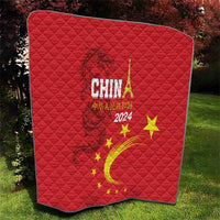Red quilt draped outdoors, China 2024 text with golden dragon swirl and yellow stars