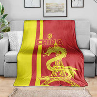 China blanket draped on gray sofa, red-yellow stripes and gold dragon with Eiffel Tower