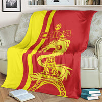 China blanket on chair with red and yellow stripes, gold dragon and Eiffel Tower graphic