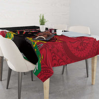 Tablecloth draped over table edge, black and red polynesian design with green accents