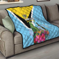 Sky blue quilt on couch with yellow triangle, black diagonal stripe, Saint Lucia crest and flowers
