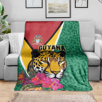 Green Guyana jaguar blanket with pink hibiscus flowers on gray sofa
