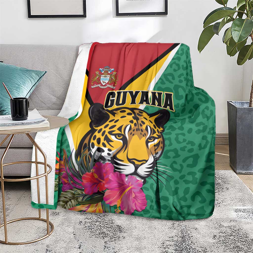 Green Guyana jaguar blanket on floor with hibiscus print and tropical leaves