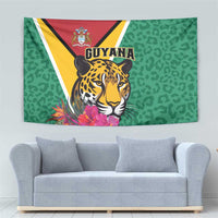 Green wall tapestry with jaguar and Guyana crest above pink tropical flowers