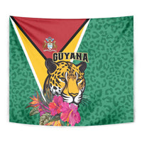 Close-up green tapestry showing Guyana crest, jaguar face, and pink tropical flowers