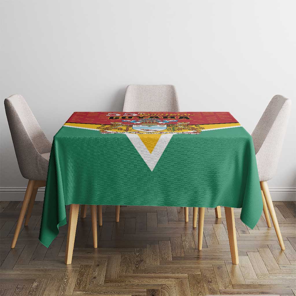 Guyana flag style anniversary tablecloth on small table, green cloth with V design