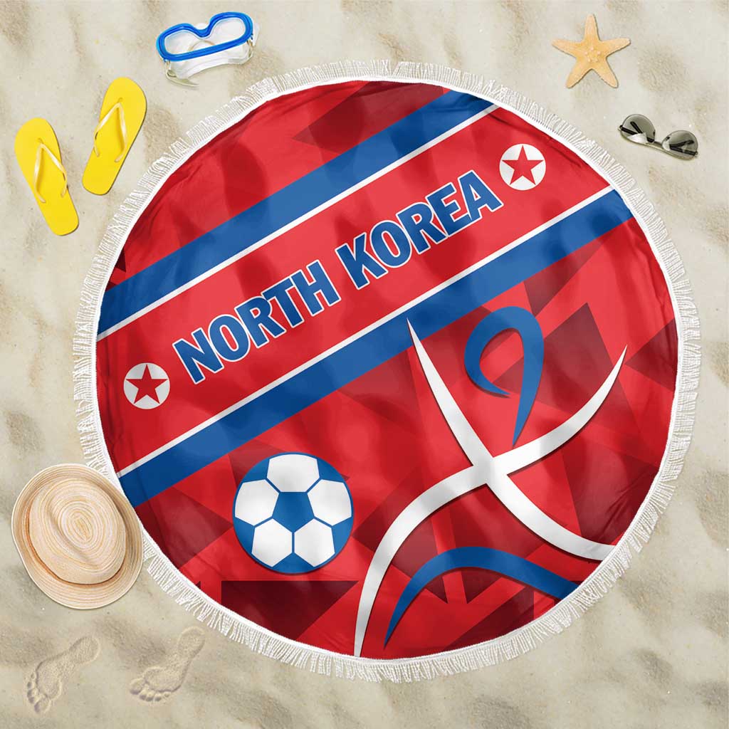 Red round football beach blanket with North Korea flag print and white fringe edge on sand