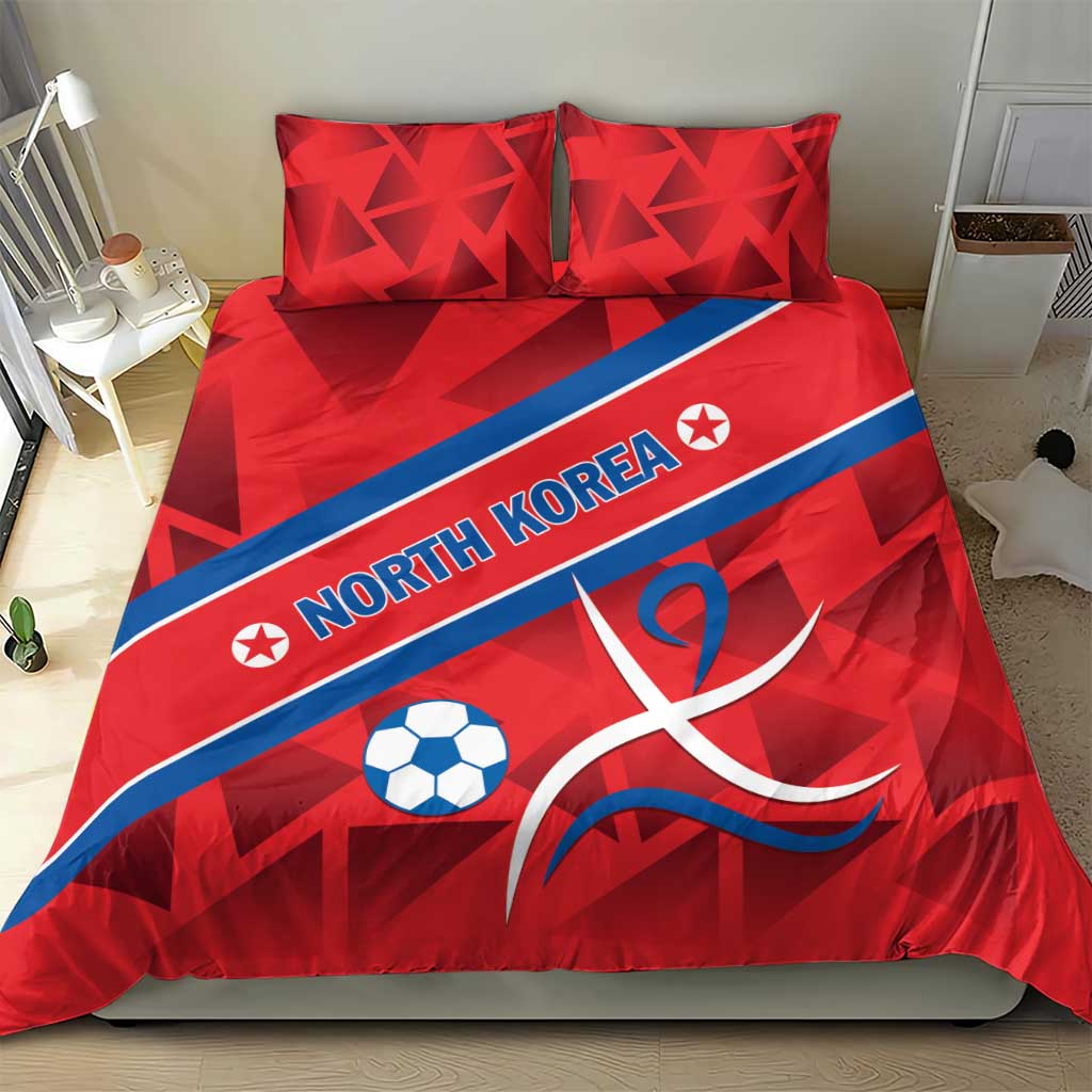 Red North Korea duvet and pillows with soccer ball and ribbon emblem, centered on bed