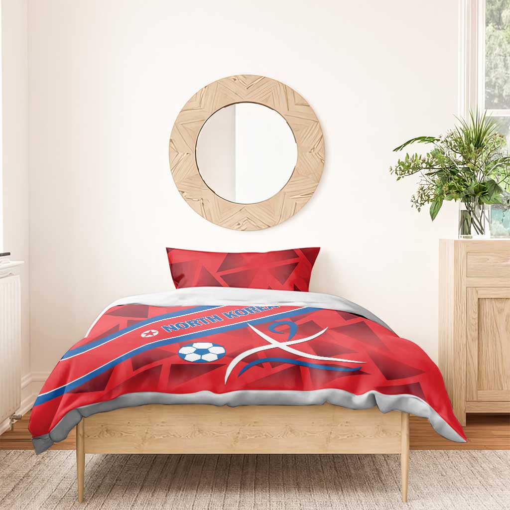 Red duvet set with North Korea text, soccer ball, and ribbon emblem, folded over bed