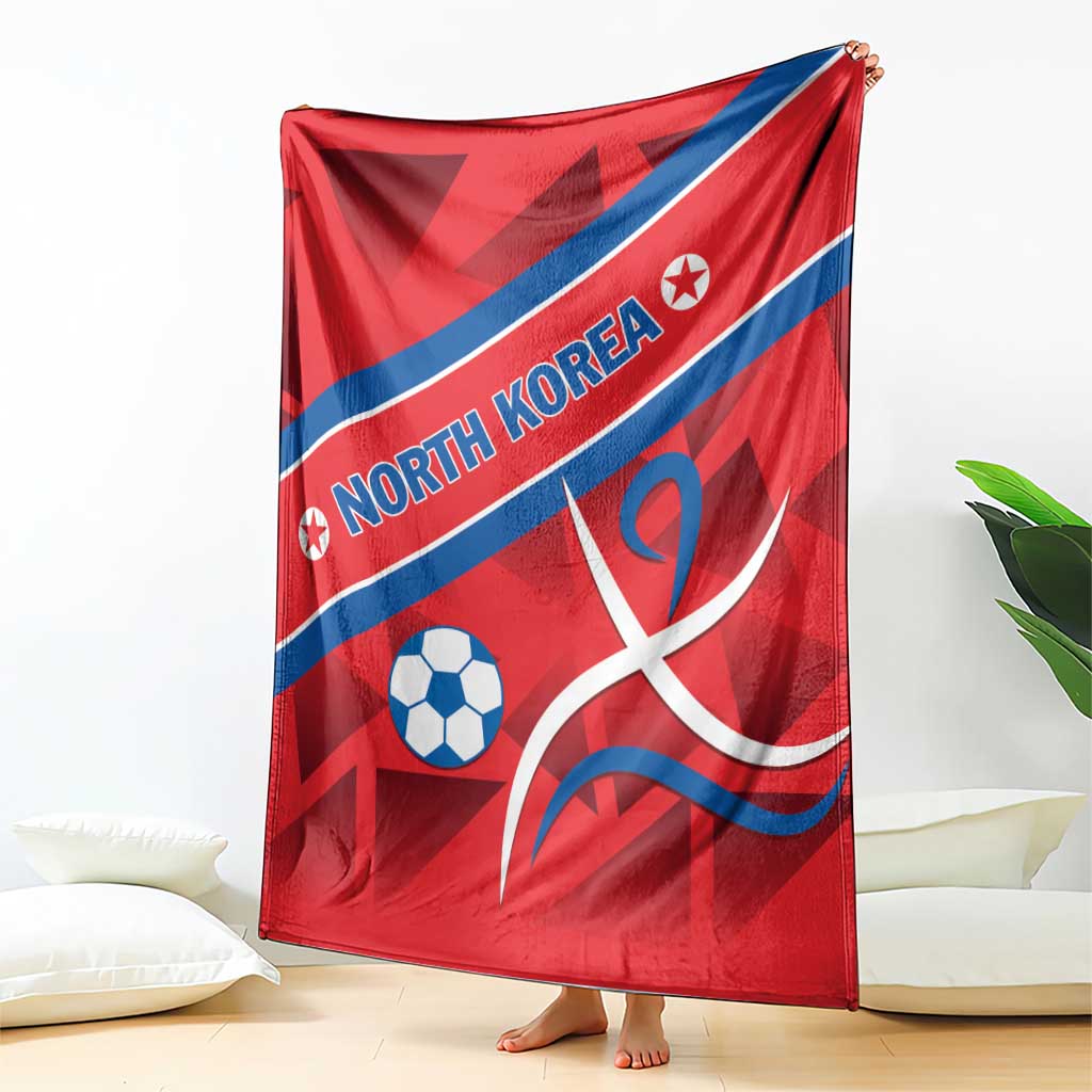 Red football blanket draped, blue diagonal stripe with North Korea text, soccer ball and emblem