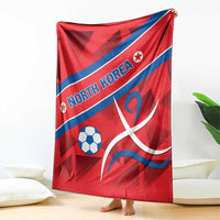 Red football blanket draped, blue diagonal stripe with North Korea text, soccer ball and emblem