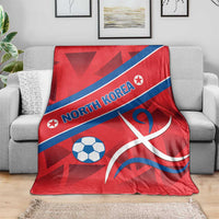Red North Korea football blanket with blue diagonal stripe, soccer ball and curved white emblem