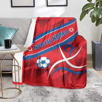 Red North Korea football blanket with blue diagonal stripe, North Korea text, soccer ball and emblem