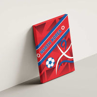 Red soccer-themed canvas wall art angled on wall with North Korea text, ball, and emblem