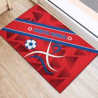 Red rubber doormat with blue stripe reading NORTH KOREA, soccer ball and swirling emblem