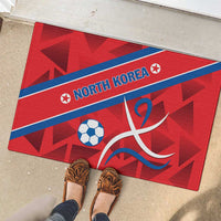 Red rubber doormat with blue NORTH KOREA band, soccer ball and taekwondo-like swirl