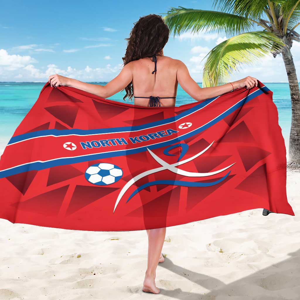 Red sarong showing NORTH KOREA text, soccer ball icons, and blue diagonal stripe
