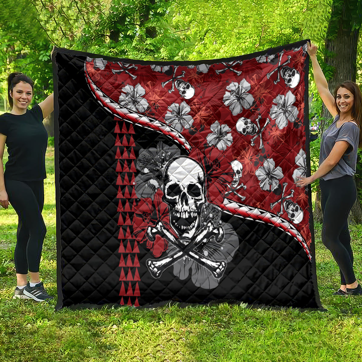Red and black Halloween quilt spread outdoors: skull and hibiscus flower print, triangle striping