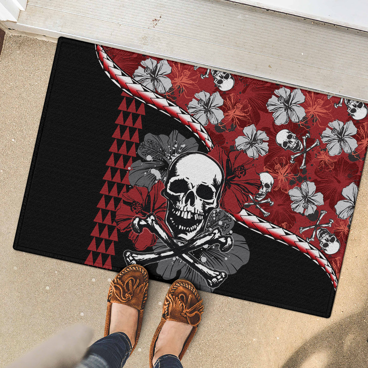 Red and black rubber doormat with skull illustration, hibiscus flowers, and black ribbed edge.