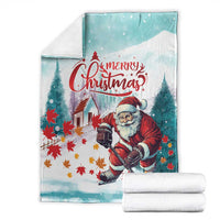 Teal Christmas blanket with Santa artwork and “Merry Christmas” banner, folded with stacks