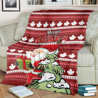 Red Christmas blanket on couch showing Santa with a present, pine trees, and maple leaf motifs