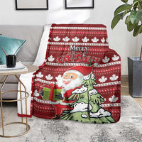 Red Christmas blanket on sofa with Santa, pine tree, gifts, and repeating snowflake stripe design