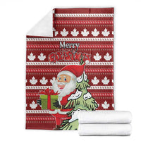 Red Christmas blanket folded with Santa and pine tree graphic on striped maple leaf pattern