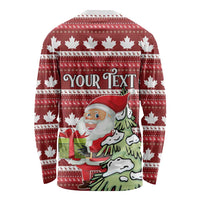 Unisex red long-sleeve Christmas shirt with white maple leaves, Santa with gift, and 'YOUR TEXT' banner