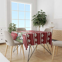 Red Christmas tablecloth on rectangular table with repeating maple leaf and Santa motifs