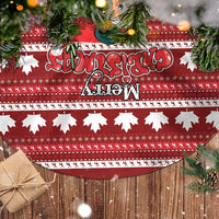 Red tree skirt with maple leaf print and fringe edge, laid on a surface