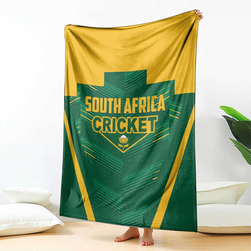 Green and yellow blanket draped on sofa, featuring South Africa Cricket logo
