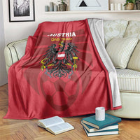 Red Austria football blanket with team text and emblem, draped over sofa