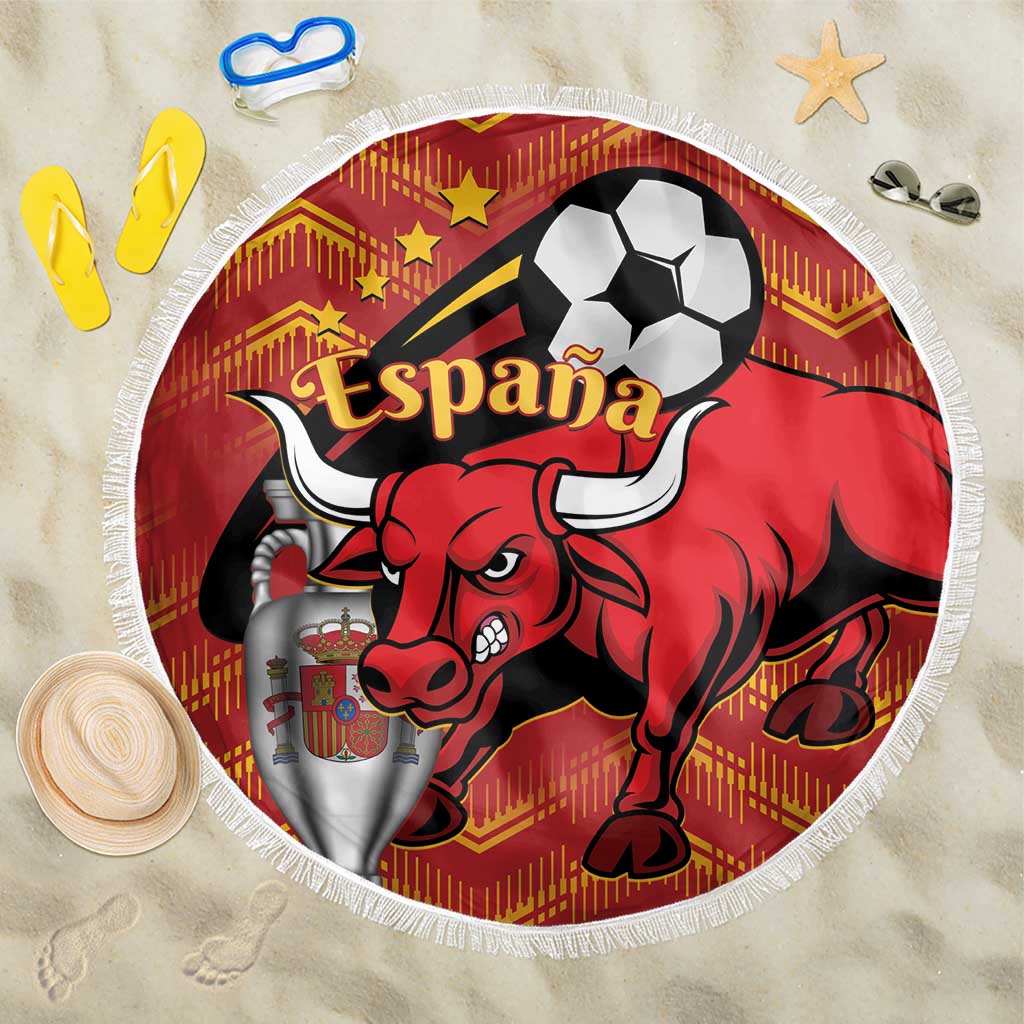 Round red beach blanket with Spain bull and soccer ball graphic, white fringe on sand.