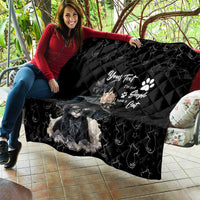 Black quilt blanket held on couch seat, featuring gray cat artwork and quilted diamond stitching