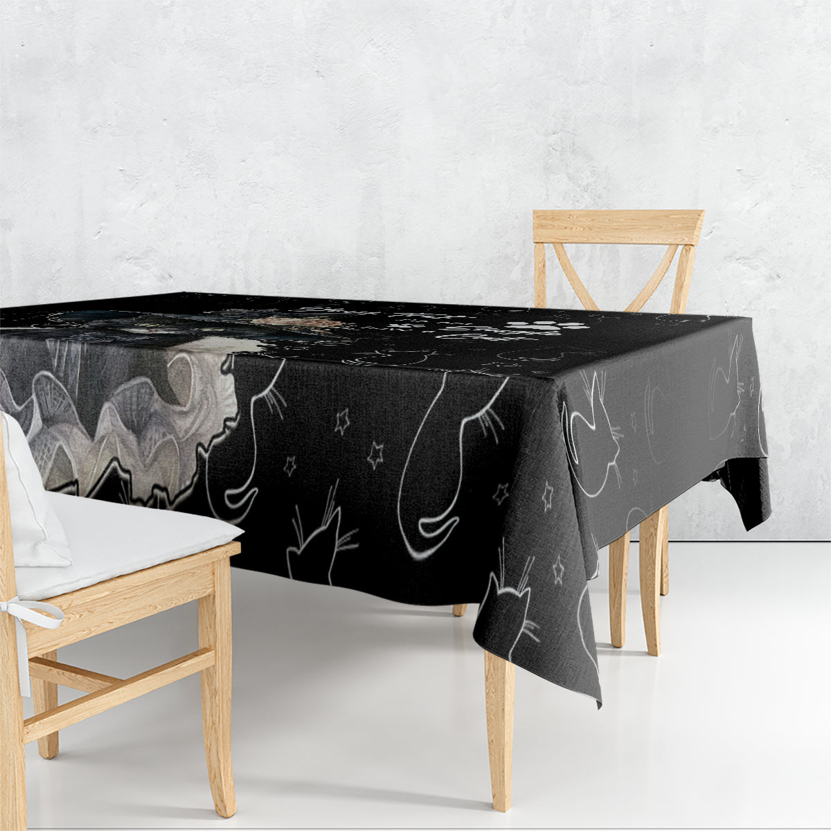 Black tablecloth over table with repeating cat and moon/star doodle pattern