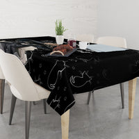 Black cat-pattern tablecloth draped over rectangular dining table with chairs