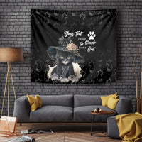 Black tapestry with illustrated cat wearing a hat, paw prints, and cursive text on it