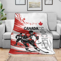 Canada hockey blanket on gray couch, red-and-white design with hockey players and maple leaves