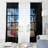 Black window curtain panels with blue-sky city print and vertical CUBA lettering, bed-side view