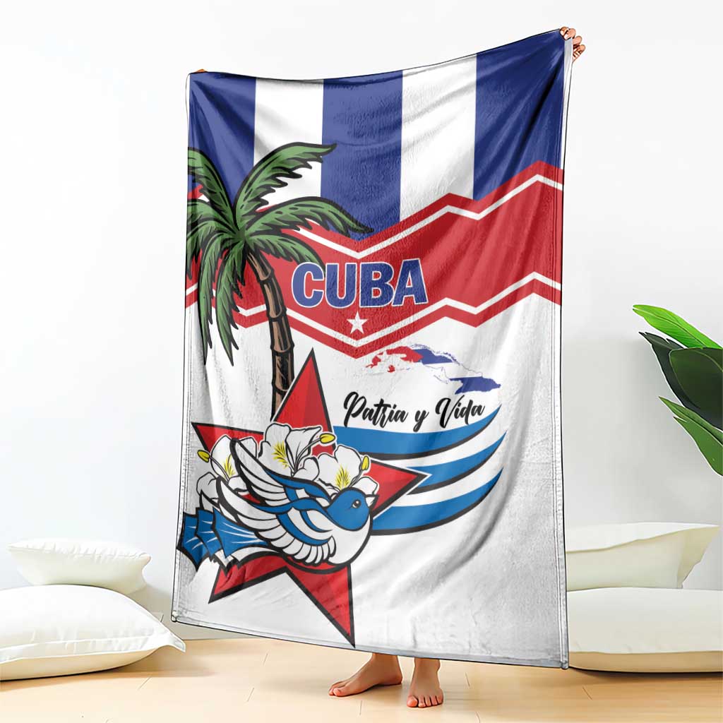 White blanket draped over sofa, featuring “CUBA” emblem, palm tree, bird, and “Patria y Vida”
