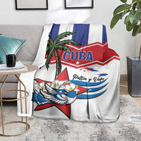 White blanket spread on floor with “CUBA” graphic, palm tree, blue bird, and “Patria y Vida”