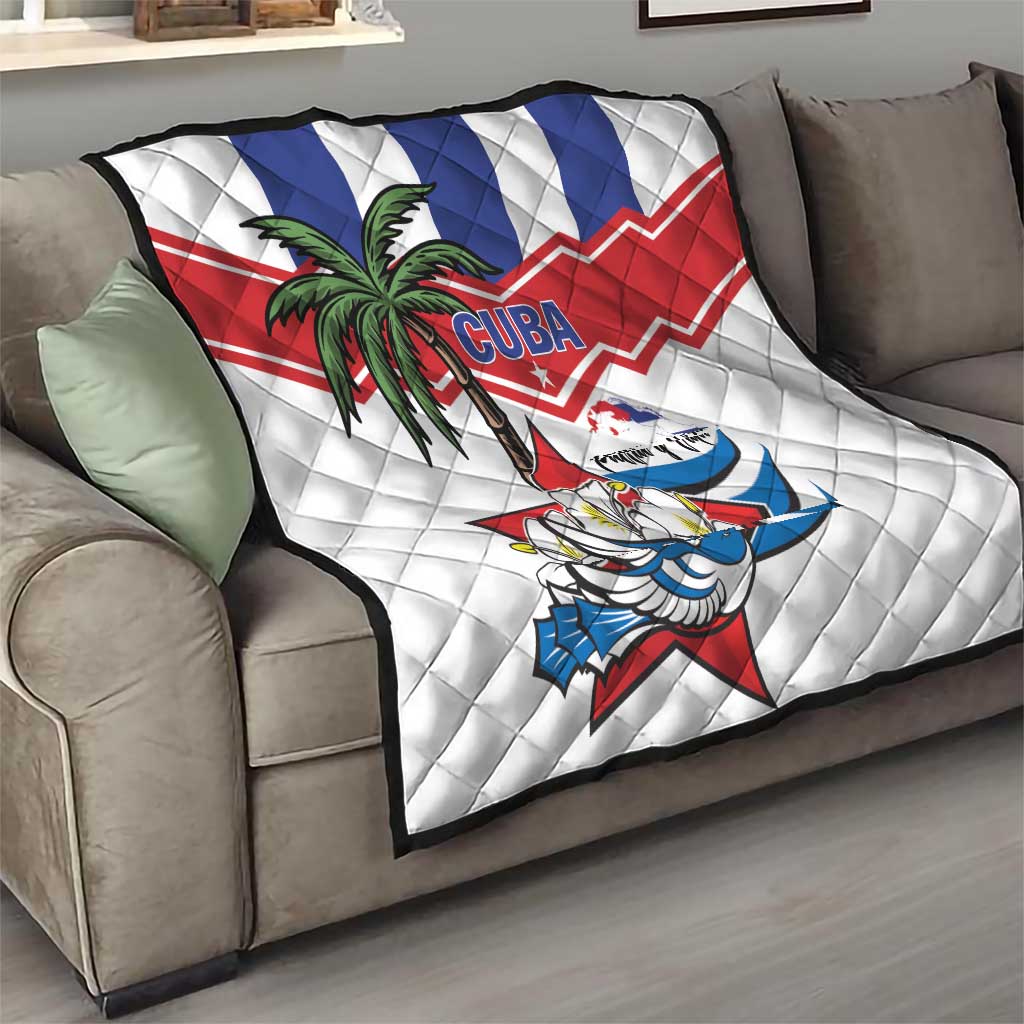 White quilt throw on gray sofa with palm tree, bird graphic, and Cuba blue/red stripes.
