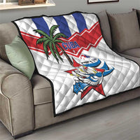 White quilt throw on gray sofa with palm tree, bird graphic, and Cuba blue/red stripes.