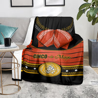 Black blanket draped on sofa featuring “Cinco de Mayo” in gold and orange panel